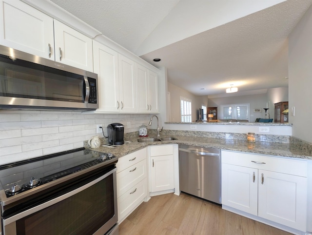 50 Pawleys Place Dr Unit 50, Pawleys Island, SC 29585 - kitchen with stainless steel appliances, backsplash, white cabinets, light wood-type flooring, and a textured ceiling