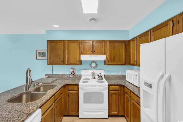 312 42nd Ave N Unit B2, North Myrtle Beach, SC 29582 - kitchen with white appliances, under cabinet range hood, brown cabinets, dark stone counters, and a peninsula