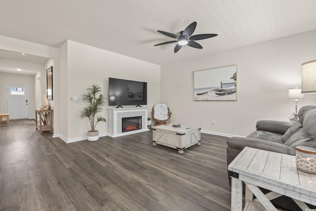 688 Wallace Dr, Little River, SC 29566 - living area featuring dark wood-type flooring, a ceiling fan, and a warm lit fireplace