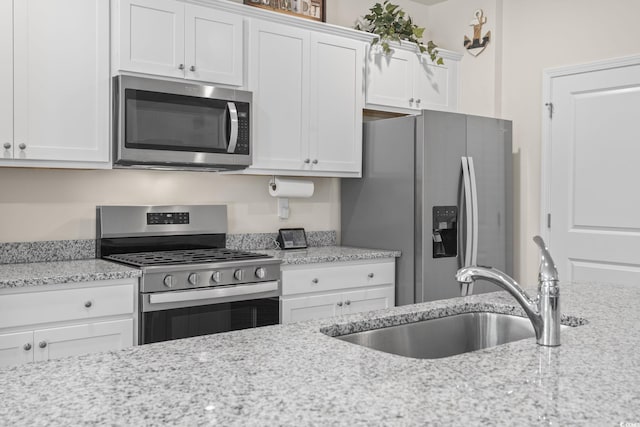 688 Wallace Dr, Little River, SC 29566 - kitchen with stainless steel appliances, white cabinetry, and light stone countertops