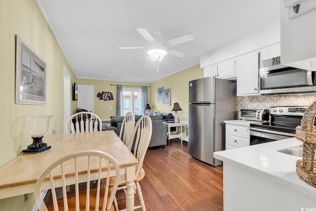 401 Hillside Dr N Unit 2F, North Myrtle Beach, SC 29582 - kitchen featuring stainless steel appliances, wood finished floors, a ceiling fan, backsplash, and white cabinetry