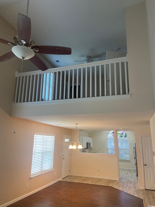 110 Palisade Loop Unit 110, Pawleys Island, SC 29585 - unfurnished living room with ceiling fan, a towering ceiling, plenty of natural light, wood finished floors, and a chandelier