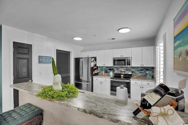 139 Butkus Dr Unit 3, Myrtle Beach, SC 29588 - kitchen with appliances with stainless steel finishes, decorative backsplash, white cabinets, and light stone counters
