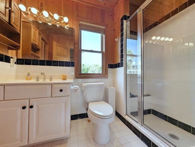 206 Atlantic Ave, Pawleys Island, SC 29585 - bathroom featuring a stall shower, vanity, wood walls, tile patterned floors, and tile walls
