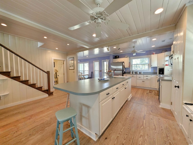 206 Atlantic Ave, Pawleys Island, SC 29585 - kitchen with ceiling fan, light wood-type flooring, a breakfast bar area, a center island, and wooden ceiling