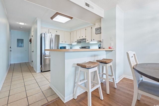 212 N 2nd Ave N Unit 162, North Myrtle Beach, SC 29582 - kitchen featuring freestanding refrigerator, under cabinet range hood, ornamental molding, a peninsula, and light countertops