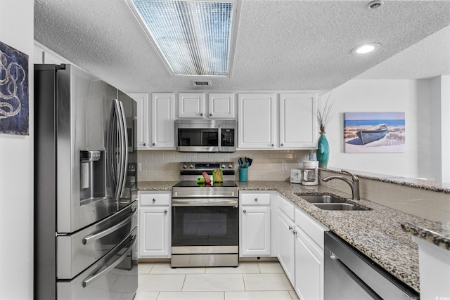 205 74th Ave N Unit 1809, Myrtle Beach, SC 29572 - kitchen with appliances with stainless steel finishes, a textured ceiling, white cabinetry, light tile patterned floors, and light stone countertops