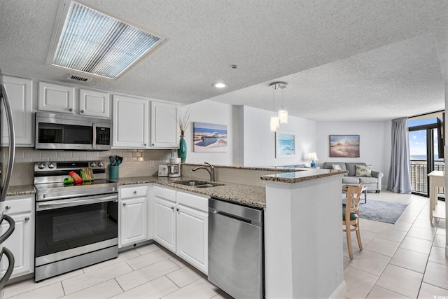 205 74th Ave N Unit 1809, Myrtle Beach, SC 29572 - kitchen with appliances with stainless steel finishes, a peninsula, open floor plan, a textured ceiling, and white cabinets