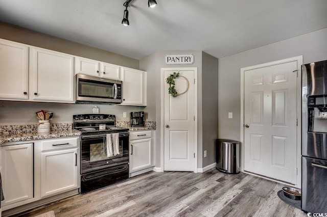 780 Trap Shooter Cir, Longs, SC 29568 - kitchen featuring stainless steel microwave, black range with electric cooktop, refrigerator with ice dispenser, light stone counters, and white cabinets
