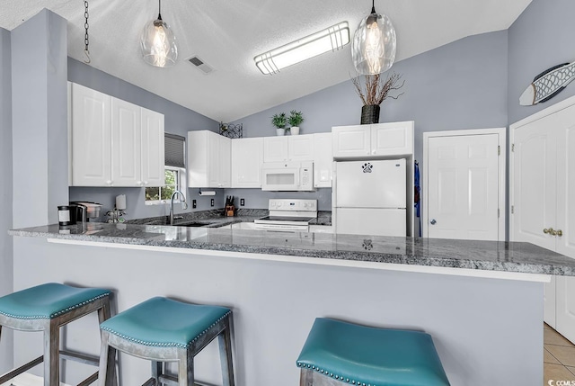 7977 Leeward Ln, Murrells Inlet, SC 29576 - kitchen featuring white appliances, vaulted ceiling, white cabinetry, decorative light fixtures, and a kitchen bar