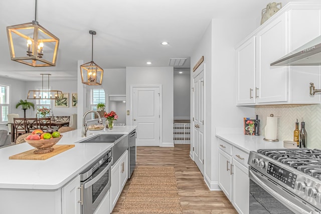 143 Enclave Pl, Pawleys Island, SC 29585 - kitchen featuring a chandelier, stainless steel appliances, light wood-style floors, tasteful backsplash, and light countertops