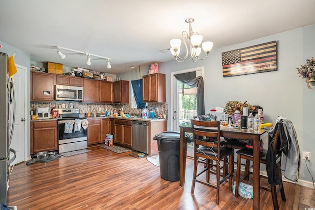 912 Clay Pigeon Ct, Longs, SC 29568 - kitchen featuring appliances with stainless steel finishes, a chandelier, wood finished floors, tasteful backsplash, and brown cabinetry