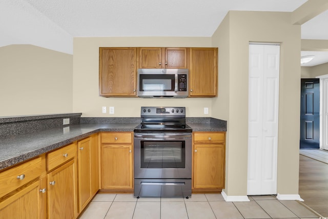 428 Bellegrove Dr, Myrtle Beach, SC 29577 - kitchen featuring appliances with stainless steel finishes, light tile patterned flooring, dark countertops, and brown cabinets