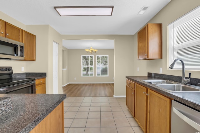 428 Bellegrove Dr, Myrtle Beach, SC 29577 - kitchen featuring appliances with stainless steel finishes, a chandelier, dark countertops, light tile patterned floors, and brown cabinetry