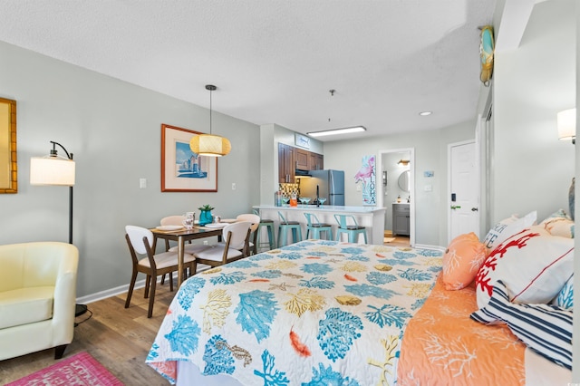1100 Possum Trot Rd Unit G117, North Myrtle Beach, SC 29582 - bedroom with freestanding refrigerator, light wood-style floors, a textured ceiling, and ensuite bathroom