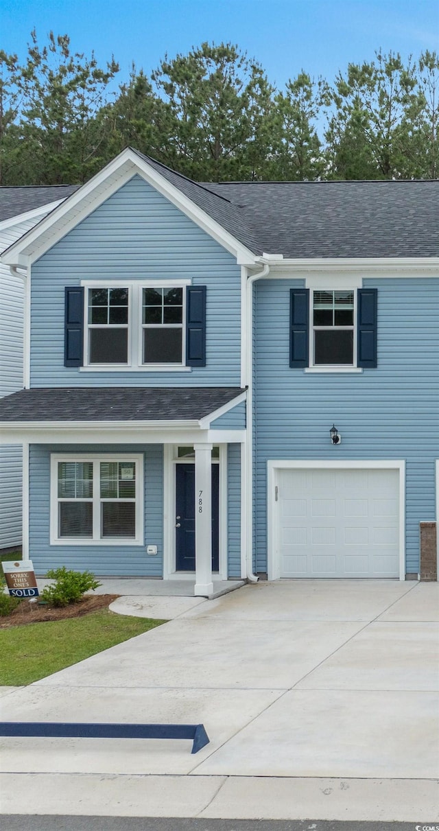 788 NW Palm Frond Way Unit 50, Calabash, NC 28467 - view of front of house with an attached garage, driveway, a porch, and roof with shingles