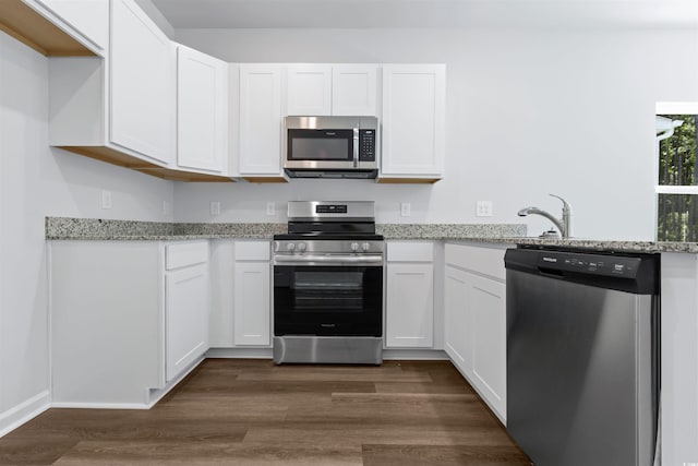 788 NW Palm Frond Way Unit 50, Calabash, NC 28467 - kitchen with appliances with stainless steel finishes, white cabinetry, light stone countertops, and dark wood-style flooring