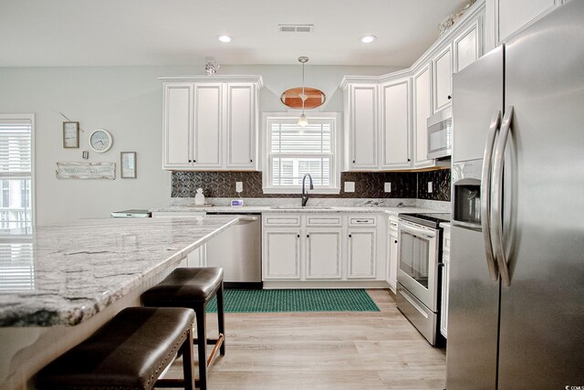 115A 8th Ave N, Surfside Beach, SC 29575 - kitchen with appliances with stainless steel finishes, light wood-style floors, white cabinets, backsplash, and recessed lighting