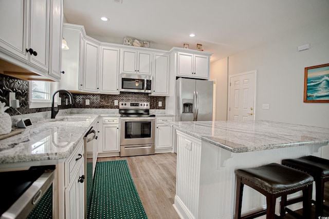 115A 8th Ave N, Surfside Beach, SC 29575 - kitchen with appliances with stainless steel finishes, light wood-style flooring, a kitchen bar, white cabinetry, and recessed lighting