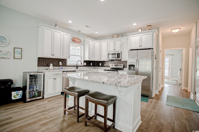 115A 8th Ave N, Surfside Beach, SC 29575 - kitchen featuring appliances with stainless steel finishes, beverage cooler, tasteful backsplash, a kitchen island, and white cabinets
