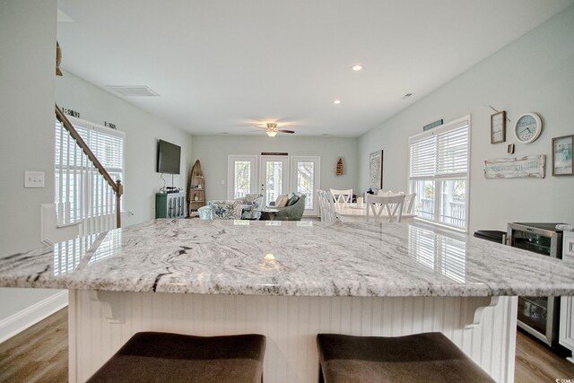 115A 8th Ave N, Surfside Beach, SC 29575 - kitchen featuring wine cooler, light wood-style flooring, a breakfast bar, light stone countertops, and a center island