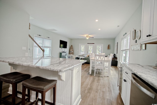 115A 8th Ave N, Surfside Beach, SC 29575 - kitchen featuring dishwasher, a breakfast bar area, light wood-style floors, ceiling fan, and light stone counters