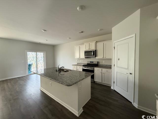 2061 Ridgedale Dr, Conway, SC 29526 - kitchen featuring appliances with stainless steel finishes, dark wood-style flooring, white cabinetry, dark stone countertops, and a center island with sink