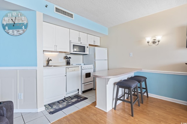 5523 N Ocean Blvd Unit 908, Myrtle Beach, SC 29577 - kitchen with white appliances, a breakfast bar, white cabinets, light countertops, and a peninsula