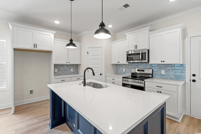 1712 26th Ave N, North Myrtle Beach, SC 29582 - kitchen with stainless steel appliances, white cabinets, tasteful backsplash, light wood-style flooring, and a center island with sink