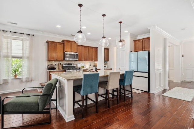 617 Carolina Farms Blvd, Myrtle Beach, SC 29579 - kitchen featuring stainless steel appliances, brown cabinets, a center island with sink, decorative backsplash, and hanging light fixtures