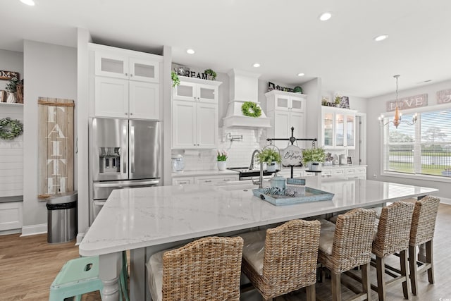 206 Palmetto Harbour Dr, North Myrtle Beach, SC 29582 - kitchen with stainless steel fridge, custom range hood, tasteful backsplash, white cabinets, and light wood finished floors