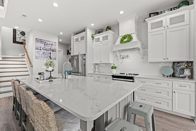 206 Palmetto Harbour Dr, North Myrtle Beach, SC 29582 - kitchen with stainless steel appliances, custom exhaust hood, a large island, white cabinets, and tasteful backsplash