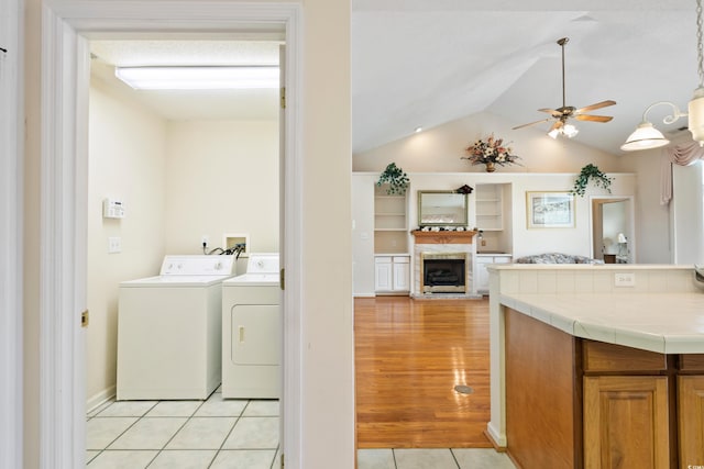 2443 Glen Dr, Little River, SC 29566 - washroom featuring independent washer and dryer, ceiling fan, a fireplace with raised hearth, and light tile patterned floors