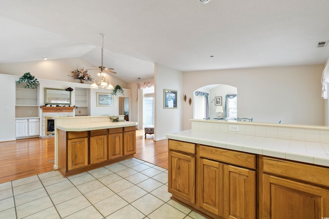 2443 Glen Dr, Little River, SC 29566 - kitchen with arched walkways, vaulted ceiling, open floor plan, ceiling fan, and brown cabinetry