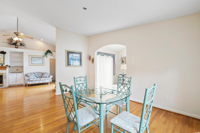 2443 Glen Dr, Little River, SC 29566 - dining room with arched walkways, light wood finished floors, a ceiling fan, lofted ceiling, and a glass covered fireplace