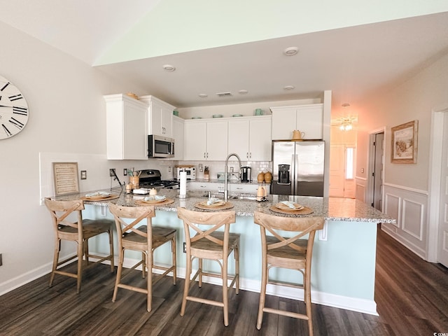 240 Sundew Loop, Little River, SC 29566 - kitchen featuring appliances with stainless steel finishes, light stone counters, dark wood-type flooring, a peninsula, and vaulted ceiling