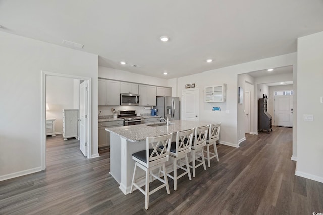 305 Picnic Basket Pl, Longs, SC 29568 - kitchen with appliances with stainless steel finishes, an island with sink, dark wood-style flooring, a kitchen bar, and gray cabinets