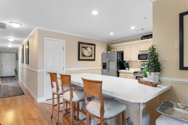 4366 Rivergate Ln Unit 404, Little River, SC 29566 - kitchen with appliances with stainless steel finishes, a breakfast bar area, ornamental molding, a peninsula, and light wood finished floors