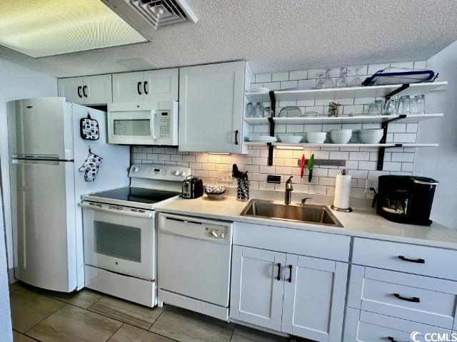 158 Sea Watch Dr Unit 707, Myrtle Beach, SC 29572 - kitchen with white appliances, open shelves, tasteful backsplash, and a textured ceiling