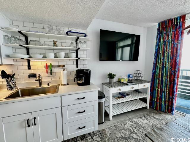 158 Sea Watch Dr Unit 707, Myrtle Beach, SC 29572 - indoor wet bar featuring a textured ceiling, tasteful backsplash, and healthy amount of natural light