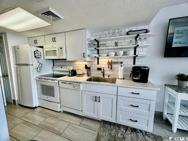 158 Sea Watch Dr Unit 707, Myrtle Beach, SC 29572 - kitchen featuring white appliances, open shelves, decorative backsplash, white cabinetry, and a textured ceiling