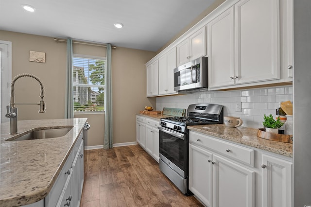 4737 Seclusion Ln, Myrtle Beach, SC 29577 - kitchen with stainless steel appliances, wood finished floors, white cabinets, backsplash, and light stone counters