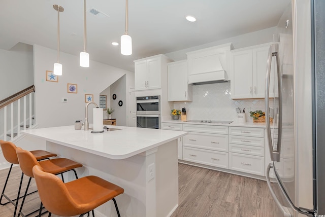 5116 Double Eagle Way Unit 49, North Myrtle Beach, SC 29582 - kitchen featuring appliances with stainless steel finishes, light wood-style floors, backsplash, white cabinetry, and a breakfast bar area