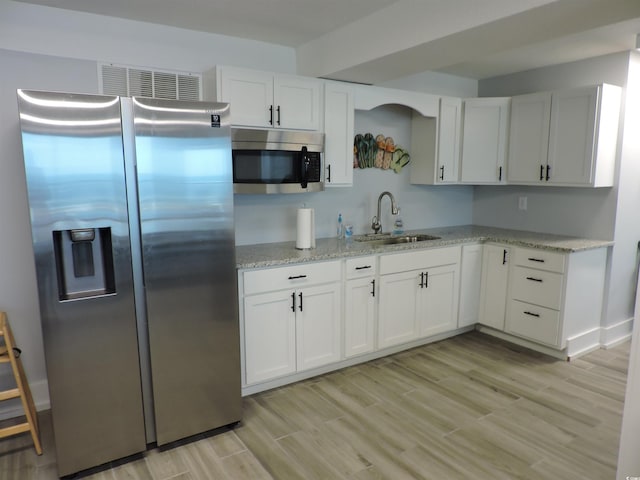 2500 N Ocean Blvd Unit 709, North Myrtle Beach, SC 29582 - kitchen featuring appliances with stainless steel finishes, light wood-style flooring, white cabinetry, and light stone counters