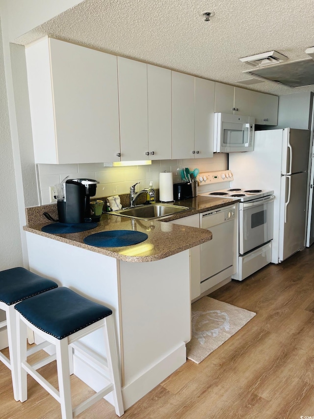 158 Seawatch Dr Unit 910, Myrtle Beach, SC 29572 - kitchen featuring white appliances, light wood-style floors, a peninsula, a textured ceiling, and white cabinets