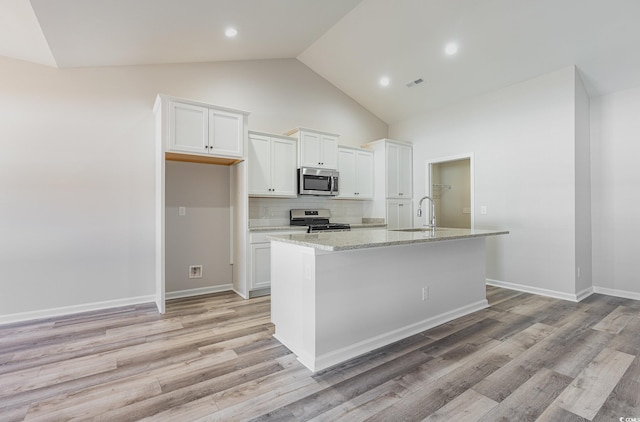 442 Lifestyle Ct, Surfside Beach, SC 29575 - kitchen with appliances with stainless steel finishes, white cabinetry, a kitchen island with sink, tasteful backsplash, and light wood-style floors