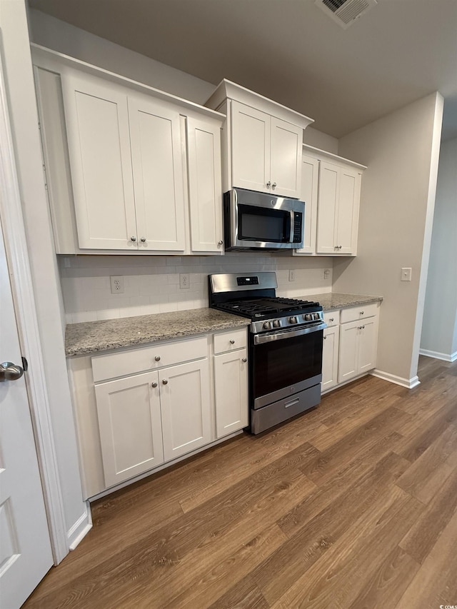 3085 Sistine St, Myrtle Beach, SC 29579 - kitchen featuring appliances with stainless steel finishes, white cabinets, dark wood-type flooring, light stone countertops, and decorative backsplash