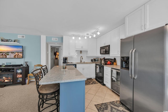 1500 Cenith Dr Unit E302, North Myrtle Beach, SC 29582 - kitchen with black appliances, backsplash, white cabinetry, a breakfast bar, and a center island
