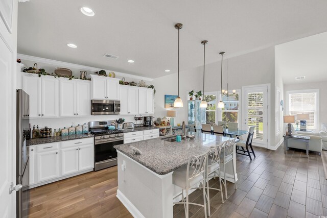 2766 Stellar Loop, Myrtle Beach, SC 29577 - kitchen with stainless steel appliances, dark stone counters, decorative light fixtures, a kitchen island with sink, and a kitchen breakfast bar