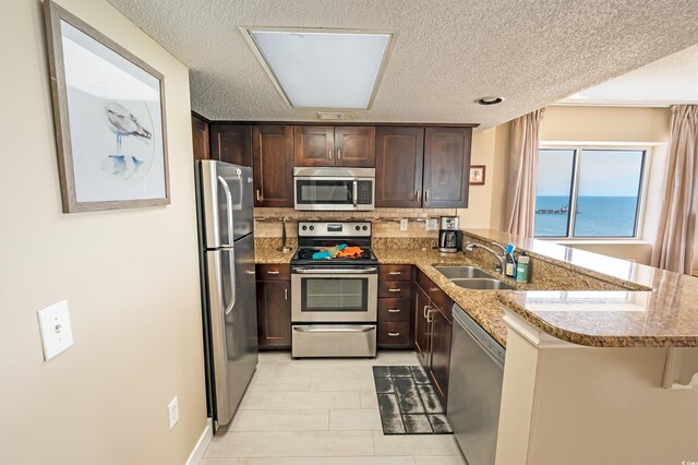 2000 N Ocean Blvd Unit 1117, Myrtle Beach, SC 29577 - kitchen featuring stainless steel appliances, a peninsula, a textured ceiling, dark brown cabinetry, and decorative backsplash